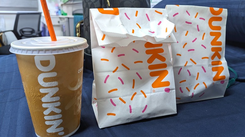 Two Dunkin' bags and a coffee on a table