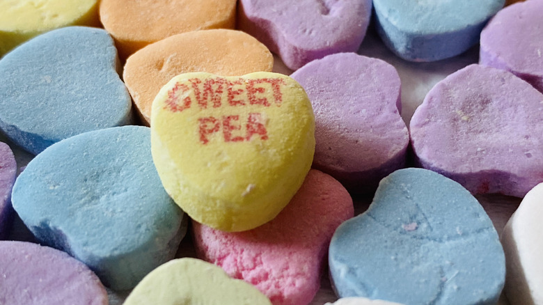 Close up of conversation hearts candies, with a yellow heart saying Sweet Pea.