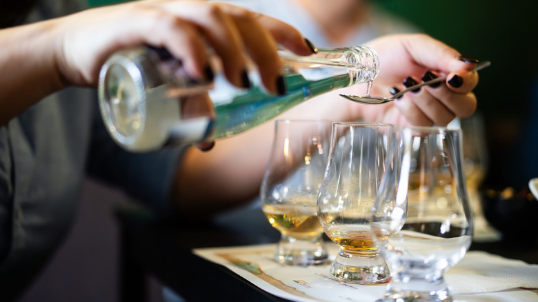 A person adds water to a whiskey glass