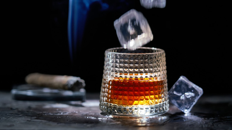 Ice cube splashing into a glass of whiskey