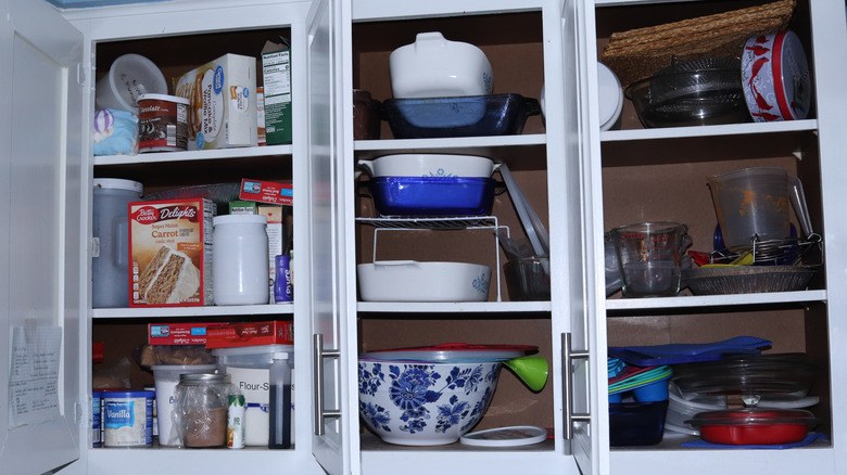Kitchen cabinet full of dishes and food boxes clutter