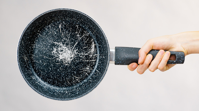 A person holds up a scratched pan