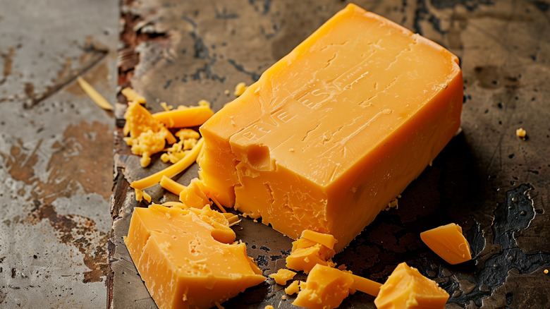 A block of sharp cheddar cheese on a rustic table