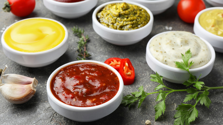 Different types of sauces in white bowls on a black table