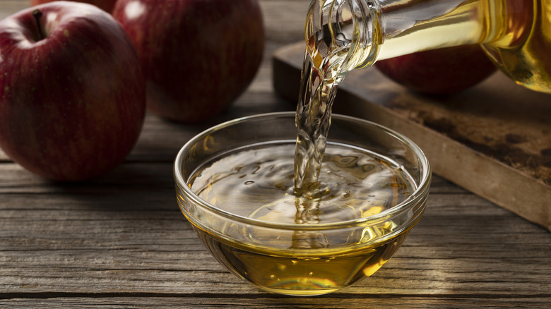 Apple cider vinegar being poured into a glass bowl