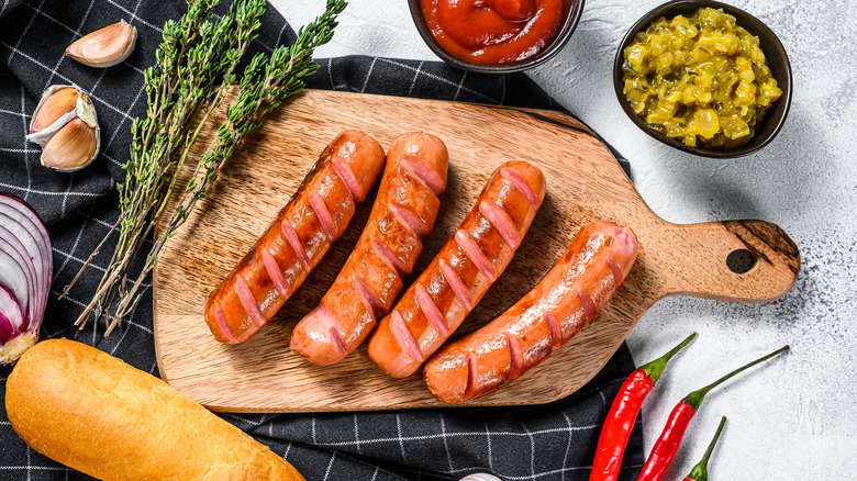 Grilled hot dogs on wooden chopping board