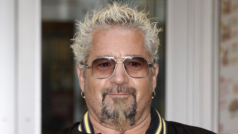 Front-facing portrait photo of Guy Fieri wearing tinted sunglasses.