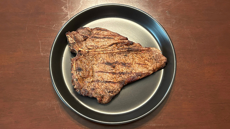 Longhorn Steakhouse T-bone steak on a black plate against a wood surface
