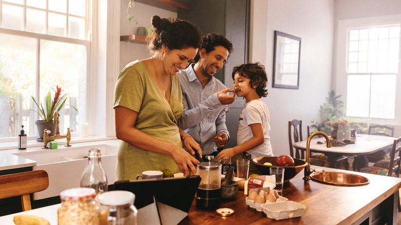 Family in the kitchen with mom, dad, and a child sitting on the counter