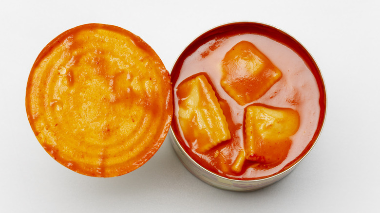 An open can of ravioli in tomato sauce on a white table
