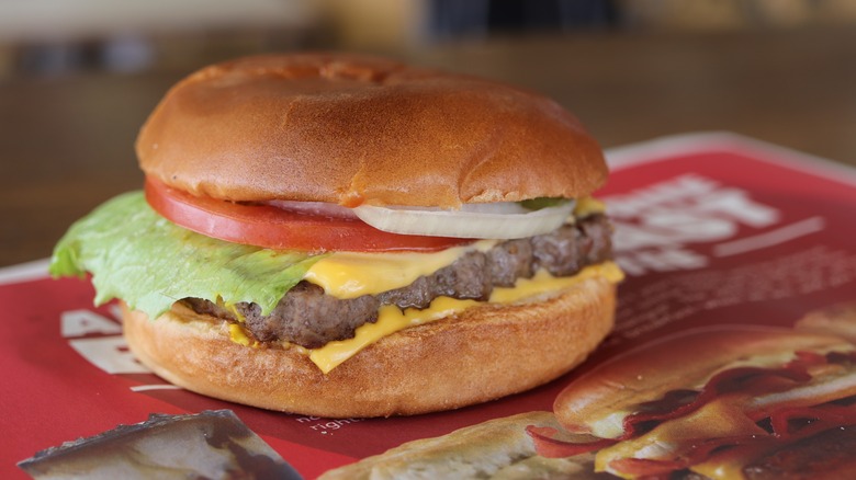 A Wendy's cheeseburger with lettuce, tomato, onions, and pickles
