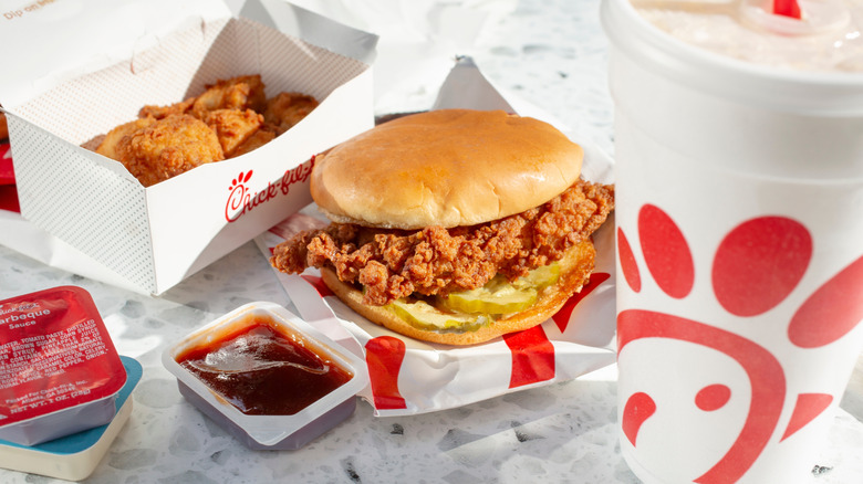 Chick-fil-A meal with chicken sandwich, sauces, nuggets, and drink on marble table