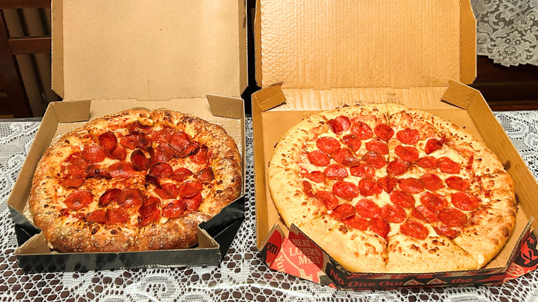 Two open pizza boxes with pizzas on a table