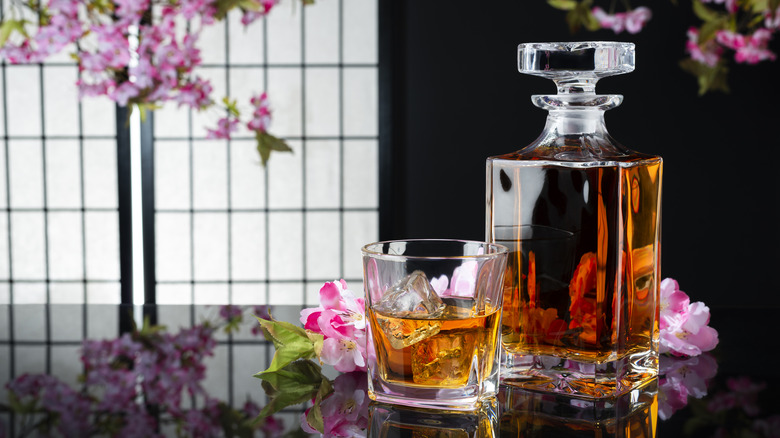 A bottle and a glass of Japanese whisky, surrounded by cherry blossoms