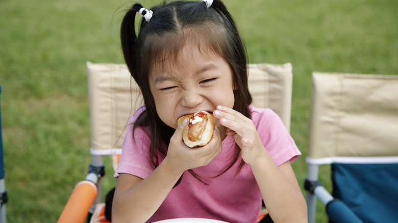 little girl eating a hot dog