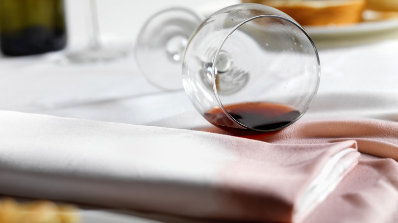 a spilled glass of red wine on a white tablecloth