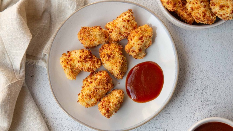 Popcorn chicken on a white plate with ketchup