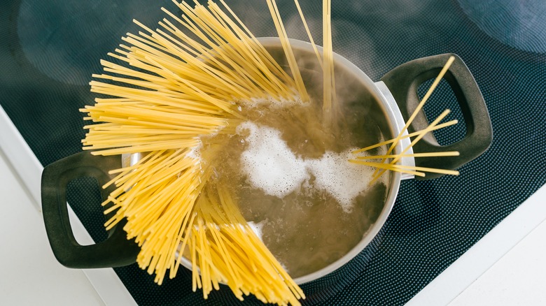 Spaghetti in pot of boiling water on stove 