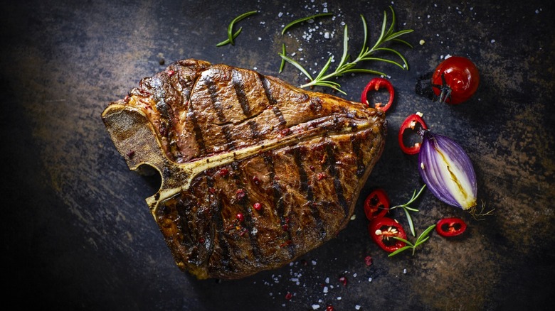 Steak with veggies, garnish, and salt on dark background
