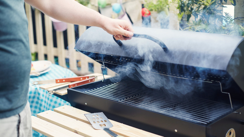A person opening a grill