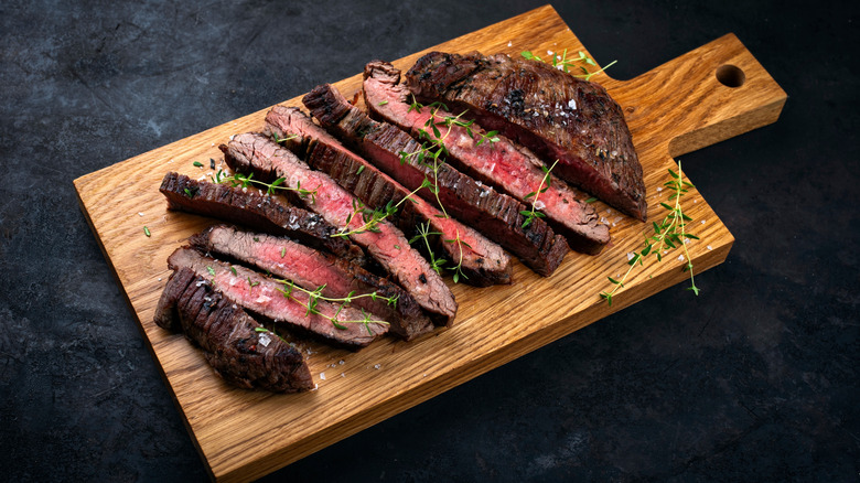 A steak, sliced open to show a medium rare cook, with a crusty browned exterior