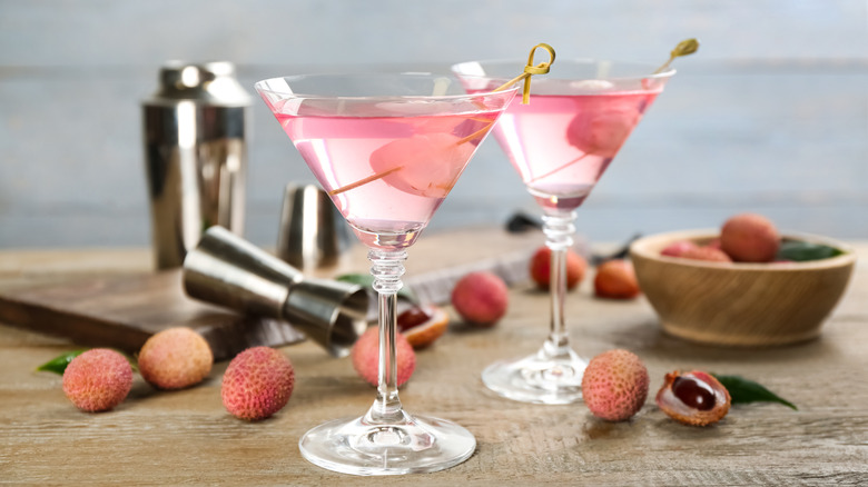 Two lychee martinis in standard martini glasses with fresh lychee scattered around the drinks