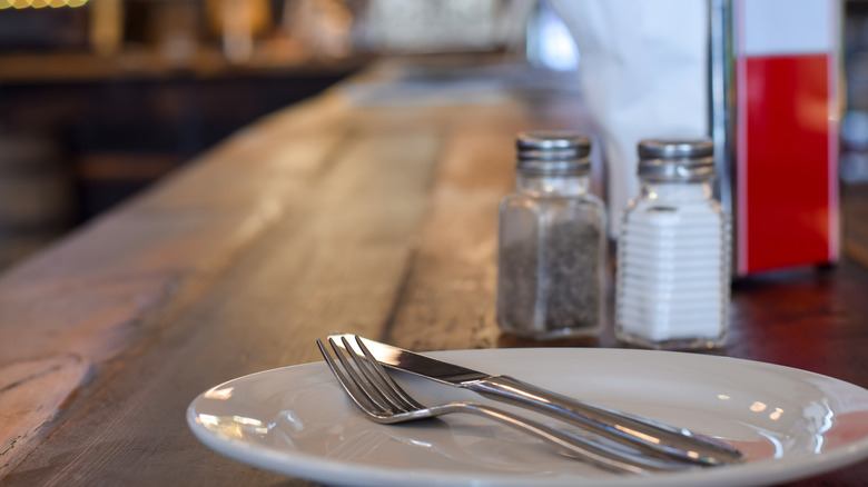A plate with a fork and knife on a quaint restaurant diner table.