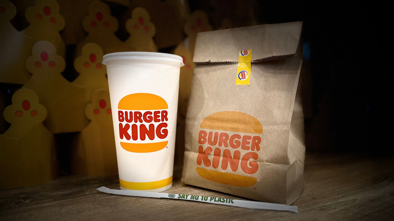 Burger King take away packaging of burger bag, soft drink cup, and straw.