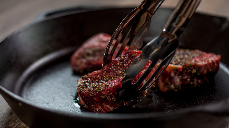 tongs touching steak